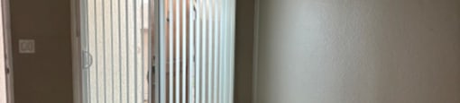 A room with wooden flooring and a sliding glass door.