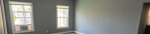 A spacious room with wooden flooring and a ceiling fan.