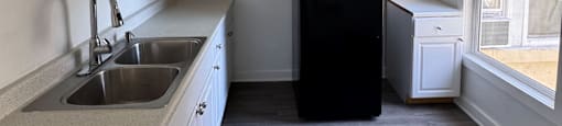 A kitchen with a sink, a refrigerator, and a window.