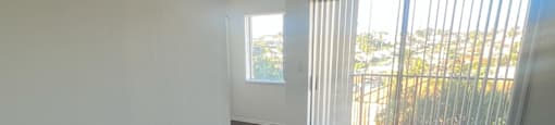 A room with wooden flooring and a window with blinds.