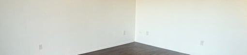 A room with wooden flooring and white walls.