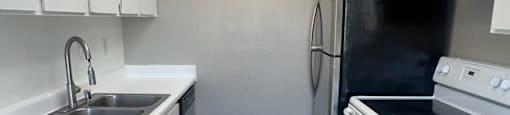 A kitchen with white cabinets and a black fridge.