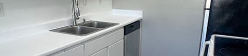 A kitchen with white cabinets and a wooden floor.