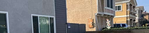 A grey house with a brown house in the background.