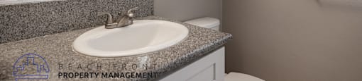 A bathroom with a granite countertop and a white sink.