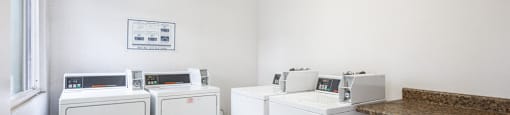 A white room with a brown counter and a fridge on the left.