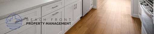A kitchen with white cabinets and a wooden floor.