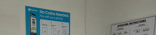 A washing machine with a sign that says "No Coins Needed" on the wall behind it.