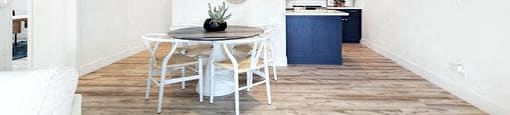 A white dining table with four chairs is in the middle of a room with a white ceiling fan.