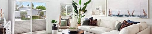 A living room with a white couch and a large window.