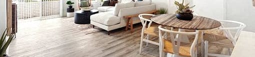 A living room with a white couch, a wooden table, and a ceiling fan.