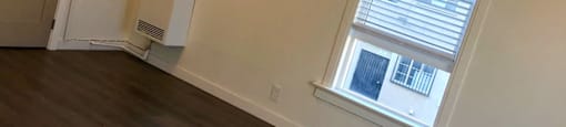 the living room of a home with a window and wooden floors