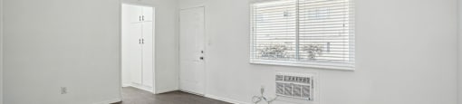 a bedroom with white walls and wood floors and a window