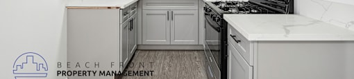 an updated kitchen with white cabinets and white marble counter tops