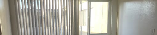 A room with wooden floors and a window with blinds.