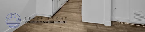 A kitchen with white cabinets and a wooden floor.