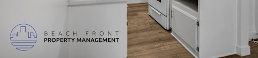 A kitchen with white cabinets and a logo for Beach Front Property Management.