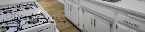 A modern kitchen with white cabinets and a stove top.