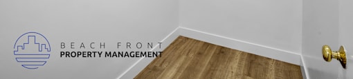 A white wall with a logo for Beach Front Property Management.