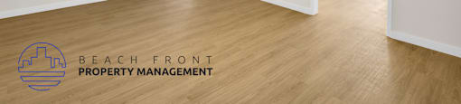 A room with a ceiling fan and wooden floors, with a logo for Beach Front Property Management in the corner.