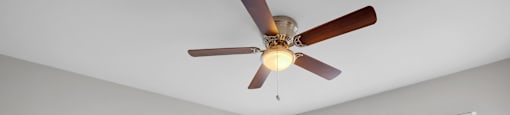 A room with a ceiling fan and a window with blinds.