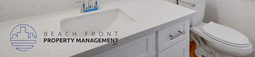 A bathroom with a white counter top and a round mirror.