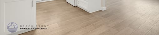 A spacious kitchen with white cabinets and a wooden floor.