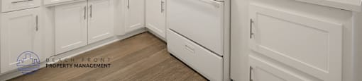 A white kitchen with a stove top oven and cabinets.