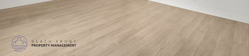 A spacious room with wooden flooring and white walls.