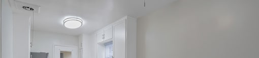 A kitchen with white cabinets and a ceiling fan.