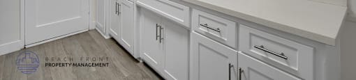 A kitchen with white cabinets and a sink under a window.