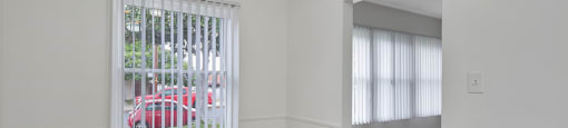 A room with a ceiling fan and a window with blinds.