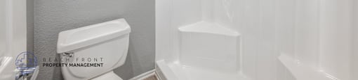 A room with wooden floors and white walls, with a window covered by a white blind.