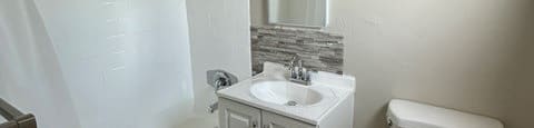 A white toilet sits next to a white sink in a small bathroom.