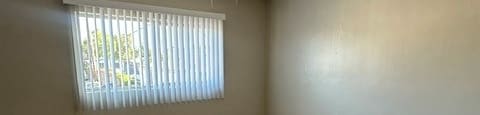 A room with a ceiling fan and a window with blinds.