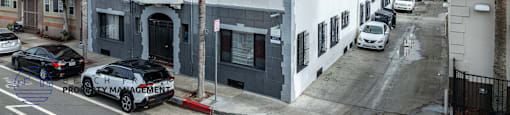 A street view of a building with cars parked in front.