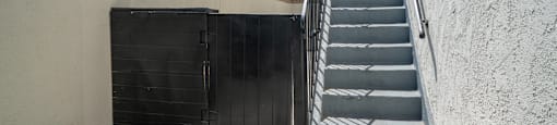 A staircase with a black door at the bottom.