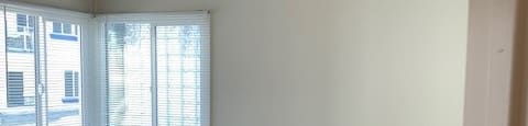 A room with a ceiling fan and a window with blinds.