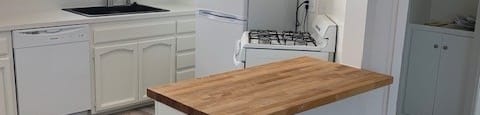 A kitchen with a white fridge and a wooden counter.