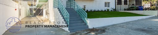 A white building with a green staircase and the words "Beach Front Property Management" on the bottom left.