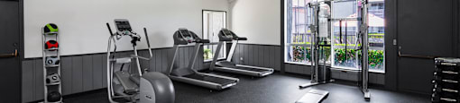 A gym with a variety of equipment including treadmills, weights, and exercise machines.