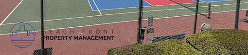 A tennis court with the words "Beach Front Property Management" on the net.