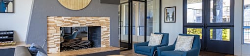 A modern living room with a fireplace and blue chairs.