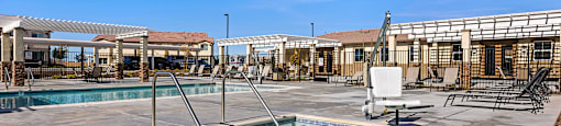 A large outdoor swimming pool with a diving board and a sun lounger.