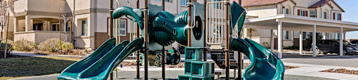 A playground with a green slide and a green canopy.