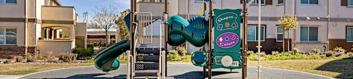 A playground with a green slide and a sign that says "Kids Play Area".