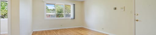 an empty living room with wooden floors and a window