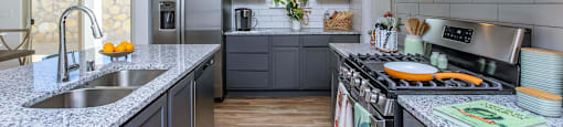 A modern kitchen with dark grey cabinets and stainless steel appliances.