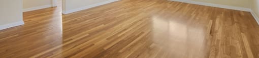 an empty living room with wood floors and a window
