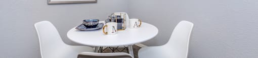 A white table with two chairs and a bowl on it.